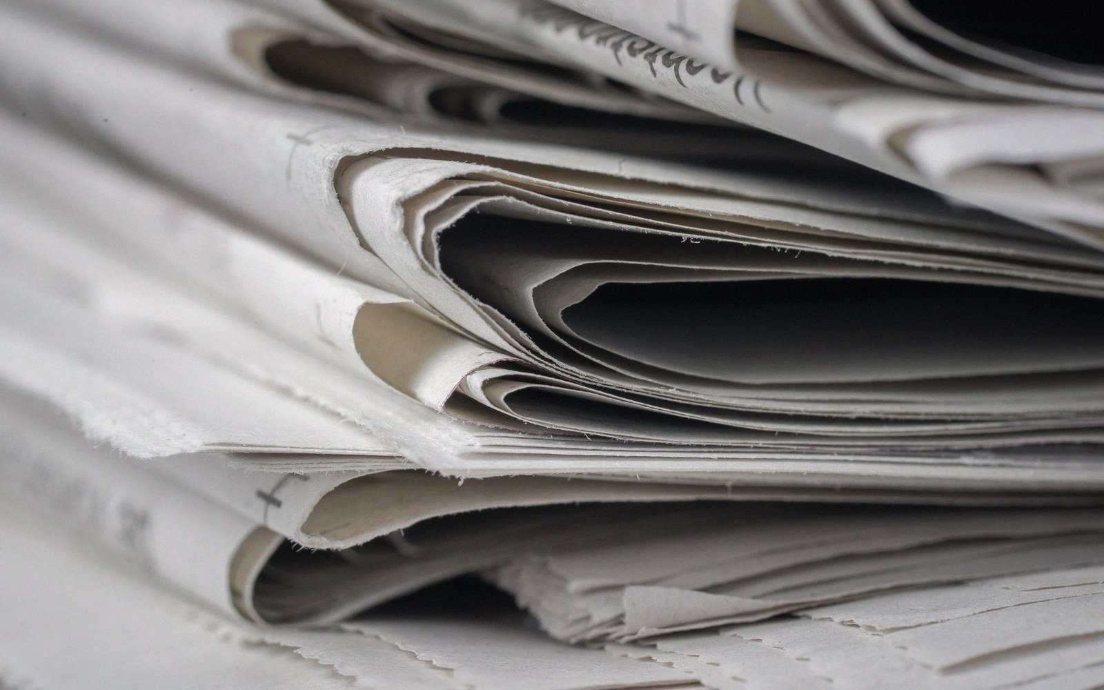 Close-up of folded newspapers stacked with their creased edges facing forward