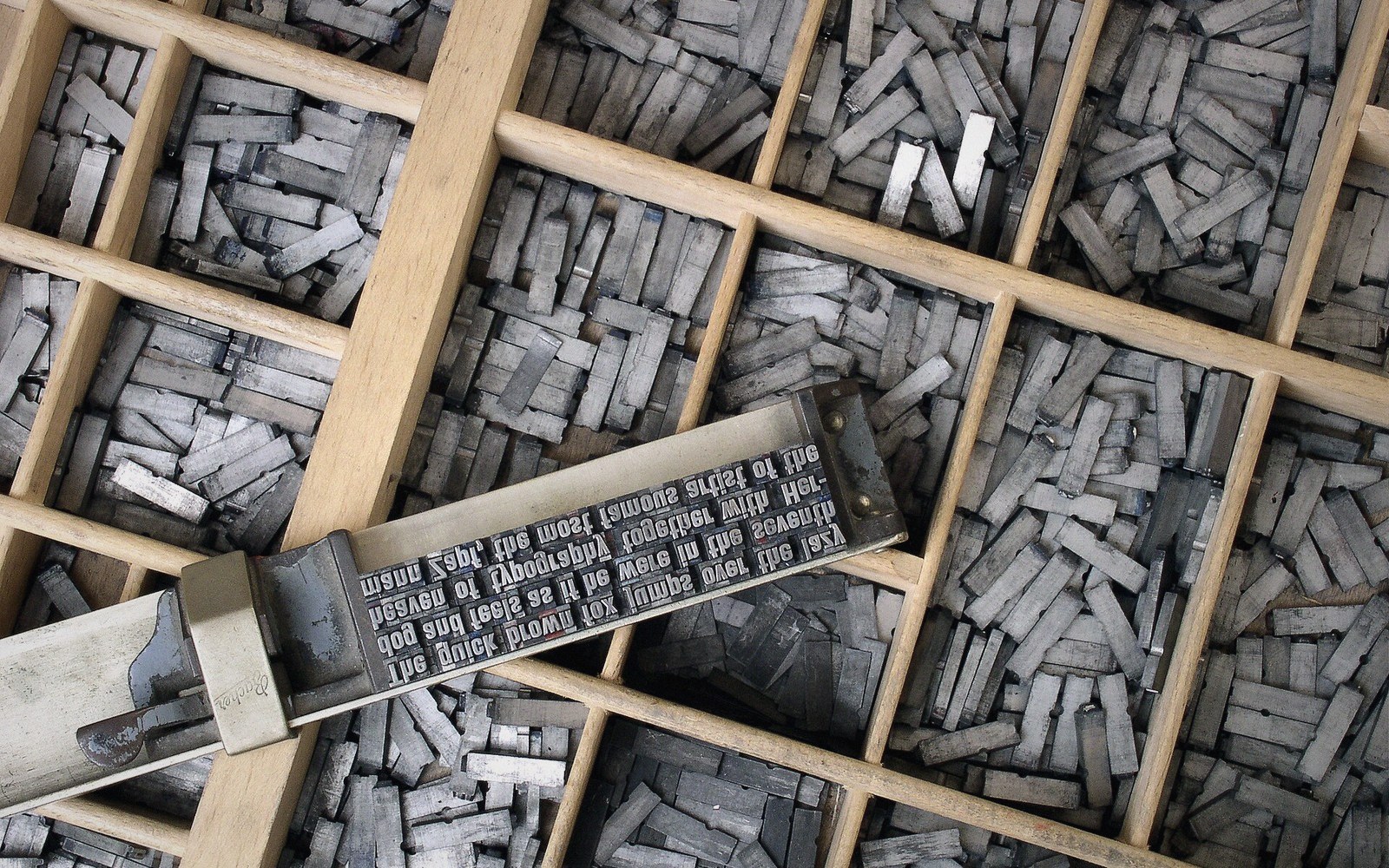 A wooden type case with compartments worn unevenly